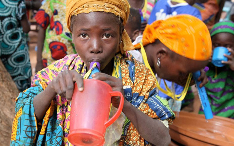 child drinking water from a Water is Life Straw
